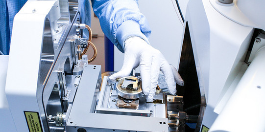 Hand im Laborhandschuh am Rasterelektronenmikroskop (REM)