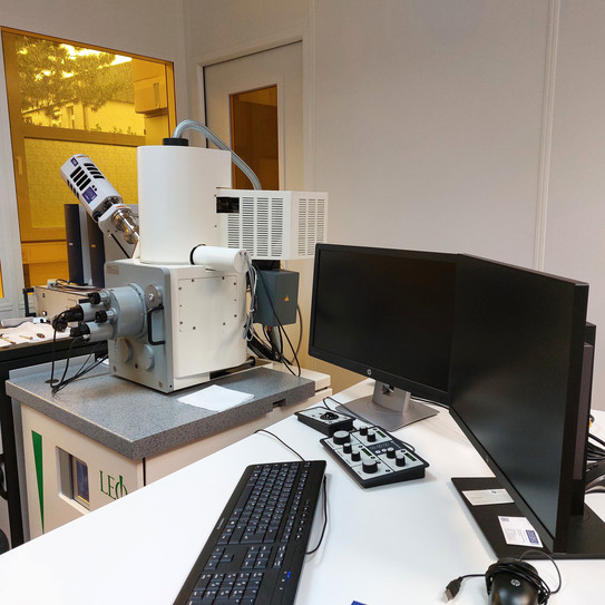 Scanning Electron Microscope (SEM) "Zeiss-LEO 982" Picture in the clean room with yellow foiled windows, shows a Scanning Electron Microscope (SEM) "Zeiss-LEO 982" with corresponding workstation in the foreground